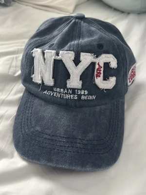Mörkblå NYC keps med brodyr - Snygg marinblå keps i vintage stil. Perfekt för soliga dagar. Justerbar storlek med hjälp av spänne där bak. 