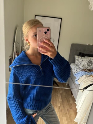 Blå stickad tröja med dragkedja - Säljer en chunky blå stickad tröja med halv dragkedja och stor krage. Tröjan har breda ribbade muddar och en avslappnad passform. Perfekt för lager på lager och riktigt snygg till jeans.