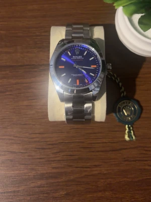 Klocka - Snygg klocka med blå urtavla och orange detaljer. Klockan har en robust länk i rostfritt stål och klassisk rund form. Den ikoniska blixtformade sekundvisaren i orange ger en unik touch. Perfekt accessoar för dig som gillar exklusiv stil. Priset kan diskuteras!
