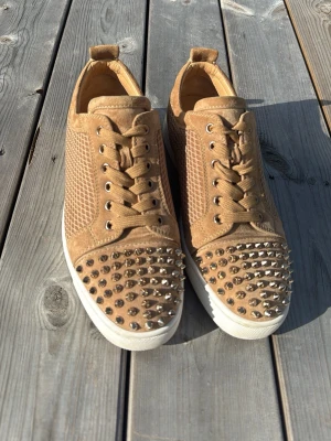 Christian Louboutin Louis Junior Spikes, stl 40,5. - Mycket fint skick (ca 9/10). Original dustbag, 2 extra skosnören, 5 extra nitar samt "Love Your Red Soles"-kort medföljer. Säljs på grund av att jag inte fått andvändning av dem. Christian Louboutin Luis junior orlato i färgen beige med ett speciellt mönster på sidorna. Ovanliga eftersom det är guldiga nitar och 5 extra guldiga nitar medföljes. 100% autentiska såklart