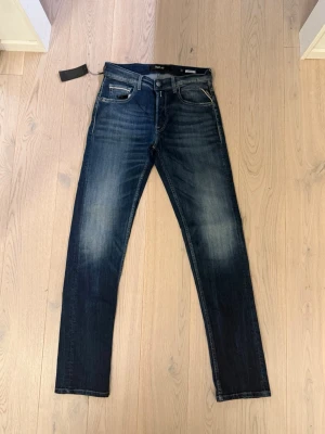 Replay Grover W29 L32 - Snygga mörkblå replay jeans modellen grieve tvättade detaljer på låren och knäna. Klassisk femficksmodell med raka ben och normal midja. Jeansen har kontrastsömmar och är tillverkade i denim med stretch för extra komfort.