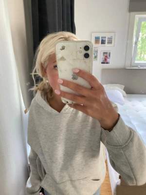 Grå hoodie Gina tricot - Säljer en ljusgrå hoodie med huva och magficka. Tröjan har ribbade muddar vid ärmsluten och en avslappnad passform. Perfekt för chill dagar och enkel att matcha med jeans eller shorts.