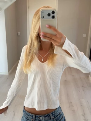 Vit ribbad topp - Såå snygg vit ribbad topp med v-ringning och långa ärmar. Toppen har en fin passform och är tillverkad i ett mjukt material. Perfekt att styla med jeans eller kjol för en fräsch look. (Inga lappar märke h&m)