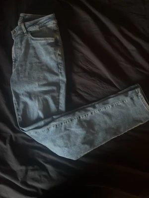 Ljusblå slimfit  - Säljer ett par ljusblå jeans med rak passform och klassisk femficksdesign. Jeansen har normal midja och stängs med dragkedja och knapp. Perfekta för en avslappnad och stilren look.