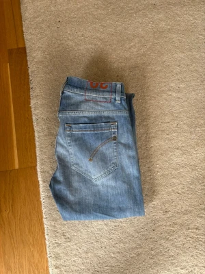 Dondup jeans  - Säljer ett par ljusblå slim fit jeans från Dondup med klassisk femficksdesign och diskreta slitningar framtill. Jeansen har normal midja och raka ben. Materialet är mjukt denim i bomull med lite stretch för extra komfort. Jeansen är sparsamt använda och är i nyskick 