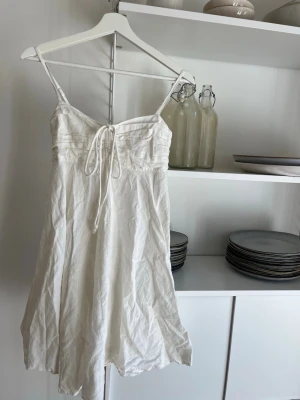 Vit kort klänning  - Söt vit kort klänning med tunna axelband och snörning framtill. Man kan antingen ha den som vanligt eller knyta den runt halsen. Använd vid 1 tillfälle, skriv för flera bilder💕