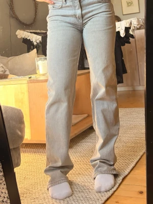 Ljusgråa raka jeans med hög midja - Säljer ett par ljusgråa jeans med rak passform och midwaist midja. Dem är från Gina tricot och köpta 700. Kommer inte längre till användning så säljer därför. Lite slitage på jeansen längst ner (syns på sista bilden)🥰🥰