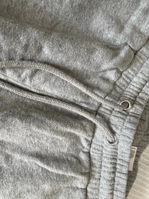 Gråa mjukisbyxor med dragsko - Snygga grå mjukisbyxor med resår i midjan och dragsko för perfekt passform. Tillverkade i mjukt sweatshirtmaterial och har ribbade muddar vid bensluten. Perfekta för chill dagar hemma eller när du vill vara bekväm.