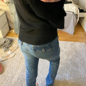 Bootcut jeans med fickdetalj - Säljer ett par blå bootcut jeans med klassisk femficksdesign och snygg fickdetalj bak. Jeansen har normal midja och utsvängda ben, perfekta till vardagslooken. Materialet är mjukt denim som ger en bekväm känsla hela dagen.