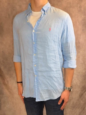 Ljusblå Ralph Lauren Linneskjorta - Stl M, custom fit - Riktig snygg Ralph Lauren Linneskjorta i ljusblå/turkos med rosa pony, perfekt till sommaren som närmar sig! 🏖️🌊 | Mycket bra skick: 9/10, utan defekter! | Stl: M |  Modellen är 177cm och väger 75kg, sitter fint men sitter även bra upp till 183cm | Hör av dig vid frågor // Galgen 🫡 