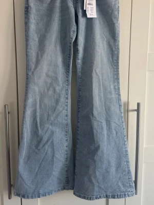 Ljusblå utsvängda jeans - Säljer ett par ljusblå jeans med utsvängda ben och klassisk femficksmodell. Jeansen har hög midja och är tillverkade i ett mjukt denimtyg. Perfekta för dig som gillar retrostil och vill ha ett par riktigt snygga jeans med 70-talsvibbar.