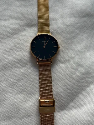 ROSÉ guldig klocka från Daniel Wellington - Stilren klocka från Daniel Wellington med svart urtavla och ROSÉ-guld. Syns inget tecken på användning alls, går att justera till den passform man vill ha. Skulle säga den är lämplig för kvinna då den är tunn/nett i modellen & urtavlan är inte så stor. Så passar bäst som tjej modell :) köparen står för frakt :) batteribyte bör göras (tror) det går att köpa/gå till en klockaffär för batteribyte :)