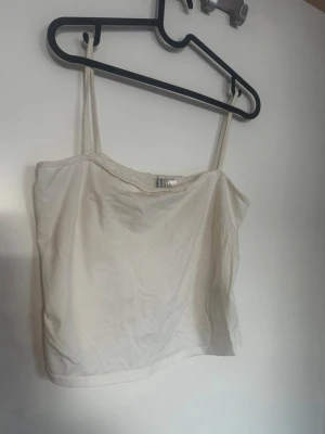 Vit enkel linnetopp med smala band - Säljer en vit linnetopp från H&M med smala axelband och rak passform. Toppen är ärmlös och har en enkel, stilren design som passar perfekt till sommaren. Tillverkad i mjuk bomull för en bekväm känsla. Rök och djurfritt hem. Pruta gärna!🌸