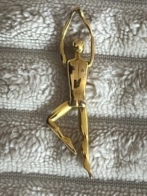 Charles Jourdan Hängsmycke Guldmetall Smycke Ledbar figur 7 - Säljer en Charles Jourdan Hängsmycke Guldmetall Smycke Ledbar figur 7 i form av stiliserade människokroppar i olika poser.  är i blankt guldfärgat metallmaterial och har en modern, konstnärlig design. Perfekta som statement-accessoarer halsband eller jacka eller väska.