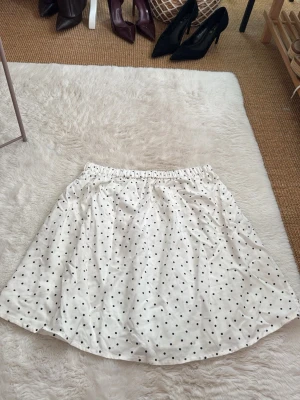 Vit prickig kjol - Söt vit kjol med svarta prickar och resår i midjan. Står tyvärr inget märke eller storlek i kjolen men passar mig som har storlek s/m 