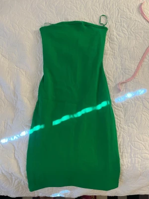 Grön ärmlös klänning med smala band - Snygg grön klänning med smala axelband och rak passform. Klänningen är ärmlös och har en enkel, stilren design som passar perfekt till sommaren. Materialet känns lätt och bekvämt.
