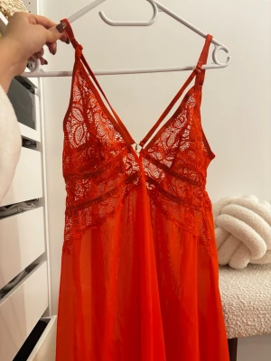  spetsnattlinne & trosor - Snyggt orange nattlinne & trosor med tunna dubbla axelband och spetsdetaljer över bysten. Materialet är lätt och transparent med vackert mönstrad spets framtill och baktill. Helt nytt. Tvättat. 