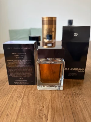 Dolce & Gabbana The One Pour Homme - Dolce & Gabbana The One Pour Homme Eau de Parfum i 50 ml flaska. Doften har inslag av tarocco apelsin, salvia och tobak. Flaskan är rektangulär i klart glas med mörkbrunt lock och elegant svart förpackning med stilren design. Även Prada luna rosa edt följer med :)