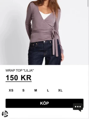 Vinröd omlottopp från 157 - Snygg vinröd  från 157 med långa ärmar och knyt i sidan. Toppen har en v-ringad design och  som känns skönt mot huden. Perfekt att styla med jeans eller kjol för en trendig look.