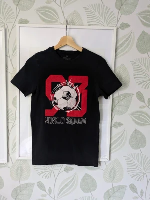 Tshirt Fotboll Storlek 146/152 H&M  - - I jättefint skick.  - Det jag hittar att anmärka på är att det förekommer små sprickor i trycket på några ställen .  - Lite ljusare nyans kan synas på söm/kant från då plagget ströks inför fotning och det brukar försvinna vid tvätt.  - Jag kan ha missat någon miniskavank men jag har försökt att granska plagget så gott det går.