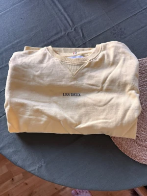 Gul sweatshirt från Les Deux - Ljusgul sweatshirt från Les Deux med rund halsringning och diskret broderad logga på bröstet. 