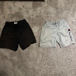3-pack shorts: Champion, Svarta, Bruna jeansshorts  - Säljer tre par shorts: ett par ljusgrå Champion shorts med snörning och logga på benet, samt ett par helsvarta shorts med dragkedjefickor och snörning i midjan Perfekta för sommaren och chill dagar.och ett par lite finare bruna jeansshorts med ljusterbar midja.  Alla säljes tillsammans