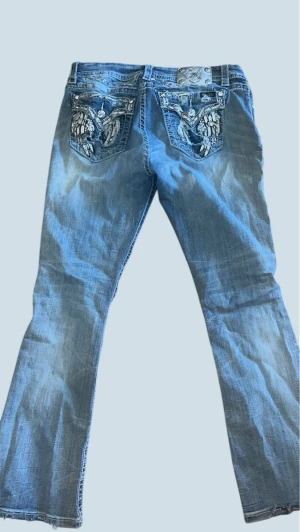 Miss Me ljus blå bootcut jeans - Säljer ett par utsvängda snygga Miss me jeans med snygga detaljer på bakfickorna. Har använt 2 gånger innan men inte mer då de inte passade mig.