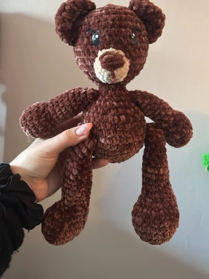 Mysig virkad brun nallebjörn - Söt handgjord nallebjörn i mjukt, brunt garn med ljusare nos och stora svarta ögon. Perfekt som present eller dekoration. Nallen har långa armar och ben, och är virkad i ett fluffigt material som känns gosigt att hålla i.