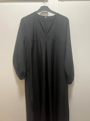 Svart abaya med lång ärm - En enkel och stilren svart abaya med lång ärm och rund halsringning med liten v-ringad öppning framtill. Abayan har en rak passform och är tillverkad i ett mjukt tyg som ger ett avslappnat intryck. Perfekt för dig som gillar minimalistisk stil.💗 pris går att diskutera 