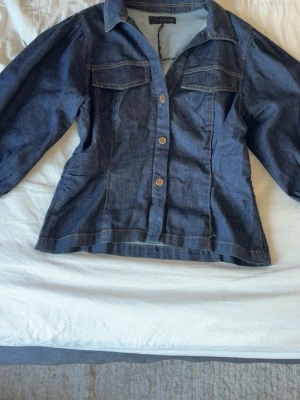 Blå jeansskjorta med knappar - Snygg blå jeansskjorta från Zara med långa ärmar och tryckknappar framtill. Skjortan har två bröstfickor och markerad krage. Perfekt för en avslappnad och trendig look.