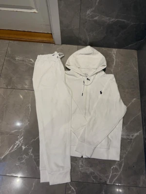 Vit loungewear-set från Polo Ralph Lauren - Snyggt vitt loungewear-set från Polo Ralph Lauren med dragkedjetröja och matchande byxor storlek S. Jag jobbar tätt intill deras kontor och får extremt bra produkter. Har flertal inne som är vunnen på auktion. Tyvärr har jag gått upp i vikt och har ingen använding för dem. Finns även andra färger, fråga för mer info.  Köper du fler blir det ett bättre pris. Fraktas direkt vid köp. 