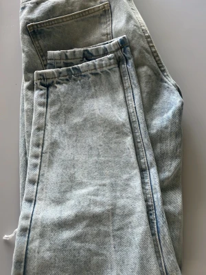 Ljusblå jeans med raka ben - Ljusblå jeans från Weekday med raka ben och klassisk femficksdesign. Jeansen har en snygg tvätt med subtila slitningar och dragkedja framtill. Perfekt för dig som gillar en avslappnad och trendig look.