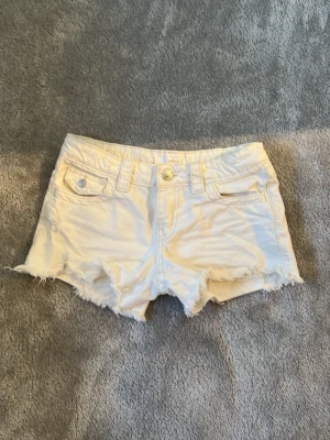 Vita Gina Tricot shorts - Snygga vita jeansshorts från Gina Tricot. Shortsen har knapp- och dragkedjestängning samt bälteshällor. Är ganska använda men har inga stora defekter.