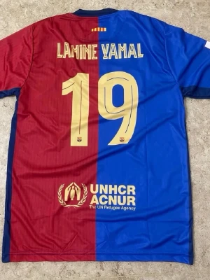FC Barcelona matchtröja Lamine Yamal - Säljer en officiell FC Barcelona matchtröja från Nike med Lamine Yamal och nummer 19 på ryggen. Tröjan är röd och blå, har korta ärmar och klubbmärket på bröstet. Materialet är lätt och andas, perfekt för fotbollsträning eller match.