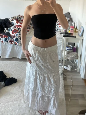 Vit långkjol med broderade detaljer - Säljer en vit långkjol med vackra broderade detaljer och volanger. Kjolen har en luftig och flowy passform, perfekt för sommar och vår. Elastisk midja för extra komfort och snyggt fall. Jag är 167.