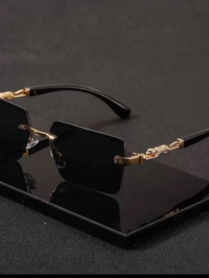 Svarta rektangulära solglasögon guld - Stilrena solglasögon med svarta rektangulära glas och tunna svarta bågar. Snygga gulddetaljer vid skalmarna ger en lyxig känsla. Perfekta för dig som vill sticka ut med en modern och edgy look. Lätta och bekväma att bära hela dagen.