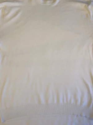 Beige stickad tröja med rund hals - En enkel och stilren beige stickad tröja med rund halsringning och långa ärmar. Tröjan har ribbade muddar vid ärmslut och nederkant, vilket ger en klassisk look. Perfekt att matcha med jeans eller kjol för en clean outfit.