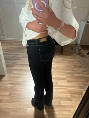 Mörkblå low waist bootcut jeans med guld detalj - Snygga mörkblå bootcut jeans med klassiska gula sömmar och guld detalj. Från Zara Woman i storlek 34/XS nypris 599kr. 