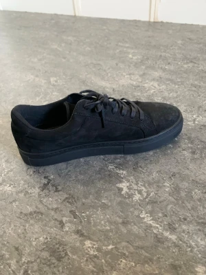 Svarta sneakers från Vagabond - Stilrena svarta sneakers från Vagabond i mocka med klassisk låg profil och svarta skosnören. Snygg minimalistisk design som passar till det mesta. Yttermaterialet är mocka och innersulan är i svart läder med Vagabond-logga.