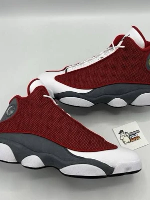 Air Jordan 13 Retro Gym Red/White - Snygga Air Jordan 13 Retro sneakers i färgerna rött, vitt och grått. Ovandelen är i röd mesh med vita och grå detaljer, samt den ikoniska hologram-loggan vid hälen. Sulan är robust och har ett unikt mönster. Perfekta för dig som gillar streetwear och basketstil.