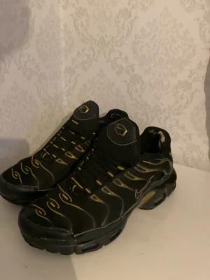 Nike Air Max Plus Tn Svart/Guld - Nike Air Max Plus Tn sneakers i svart med guldiga detaljer och mönster. Lite slitna på Insidan, Nya sulor