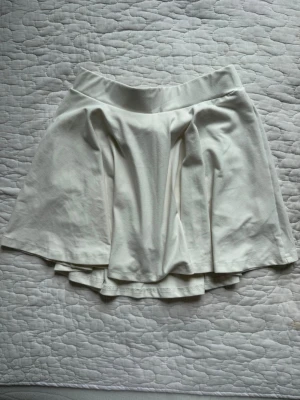 Vit kortkjol med shorts under ”tenniskjol” - Supersöt vit kortkjol med inbyggda shorts under, perfekt för en aktiv och bekväm stil.  Kläderna ligger i flyttlåda därav skickas inte fler bilder. 