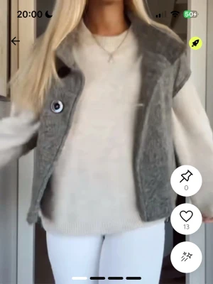 Grå stickad väst med knappar - Snygg grå stickad väst med stora knappar framtill. Västen har en öppen design och är perfekt att slänga över en tröja för en avslappnad look. Passar till både jeans och leggings för en trendig stil.