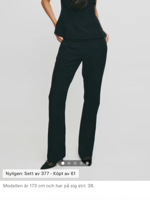 Svarta kostymbyxor med raka ben - Snygga svarta kostymbyxor med klassisk rak passform och normal midja. Byxorna har en stilren look och passar perfekt till en dressad outfit. Materialet ser ut att vara vävt tyg som ger en elegant känsla. Perfekta för dig som vill ha en clean och tidlös stil.