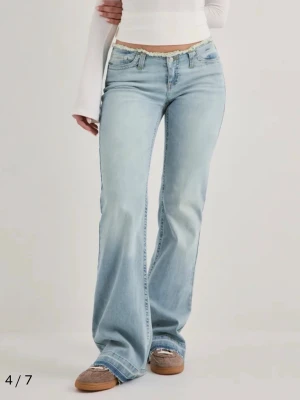 Bootcut jeans i ljusblå denim från Nelly - Bootcut jeans i ljusblå denim från Nelly med klassisk femficksdesign och låg midja. Jeansen har utsvängda ben och subtila slitningar för en avslappnad look. Perfekta för dig som gillar en retroinspirerad stil. Helt nya jag har inte använt dom en enda gång då dem var för stora. Pris går att diskutera💕