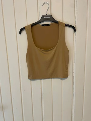 Beige croppad linnetopp från Bik Bok - Snygg beige croppad linnetopp från Bik Bok med breda axelband och rundad urringning. Perfekt att styla med jeans eller kjol för en trendig look. Tunt och mjukt material som känns skönt mot huden.
