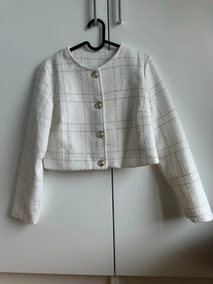 Kavaj - Kavaj i bouclé-liknande material och kortare i modellen. Mycket sparsamt använd. 