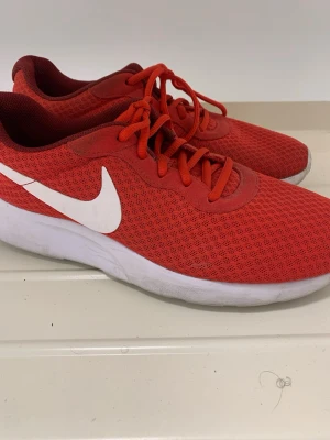 Röda Nike sneakers med vit sula - Snygga röda Nike sneakers med vit sula och klassisk vit swoosh på sidan. Ovandelen är i meshmaterial som andas och skorna har röda skosnören. Perfekta för en sportig och avslappnad stil. Storlek 42, Finns i Norrköping 