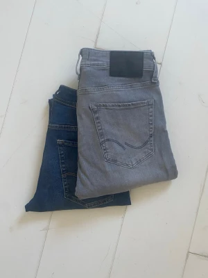  jeans från Jack and Jones  - Snygga grå slim fit-jeans från Jack & Jones med klassisk femficksdesign och svarta detaljer på bakfickorna. Jeansen har en lätt tvättad look och är tillverkade i mjuk bomullsdenim med stretch för extra komfort. Helt nya. Nypris 900 kr/st (1 800 kr för båda). Skriv vid frågor! W28/L31.”