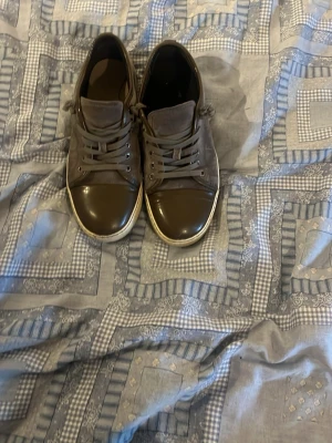 Grå sneakers med mockadetaljer - Snygga lanvins med lågt skaft och snörning. Skorna har en mix av mocka och glansigt material på tån och runt kanten. Sulan är vit och ger en fräsch kontrast. Perfekta för en stilren och avslappnad look. Skick 8/10. Bara att höra av er vid minsta fundering! MVH Joel